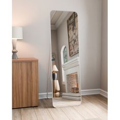 a large mirror sitting on top of a hard wood floor next to a table and lamp