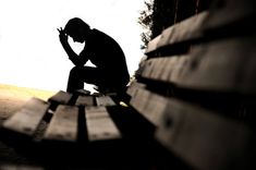 a man sitting on top of a wooden bench