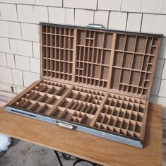 an open briefcase sitting on top of a wooden table next to a white brick wall