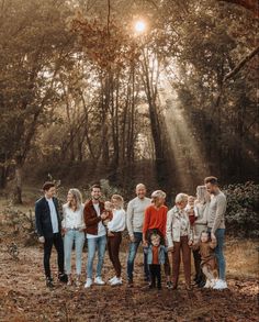 a group of people standing next to each other in front of trees and leaves on the ground