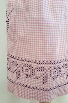 a pink and white checkered dress with black letters on the chest, along with an embroidered design