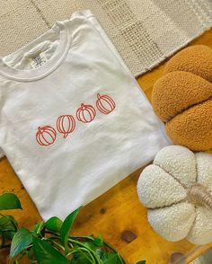 a white t - shirt with pumpkins on it sitting next to some stuffed animals