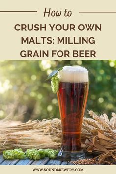 a glass of beer sitting on top of a table next to hops and wheat