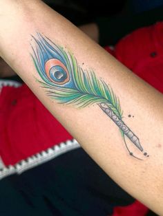 a woman's arm with a peacock feather on it and a pen in the middle