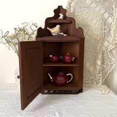 a wooden cabinet with two teapots on it and a shelf in the corner