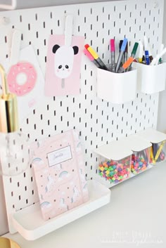 a white desk topped with lots of crafting supplies next to a wall mounted memo board