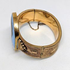 "This antique Victorian era bracelet (circa 1880s) features an oval portrait after the artist Gustav Richter titled \"Neapolitan Fisher Boy\" -- also sometimes seen as titled \"Young Vagabond.\"  The bracelet is gold tone (I believe rolled gold) with intricate floral etchings. The safety chain is still intact.   The person in the portrait is entitled a boy, but he has very androgynous features -- indeed, until I found the title of the original portrait, I thought it was a young woman with a wind Era Bracelet, Oval Portrait, Short Dark Hair, Heirloom Jewelry, Miniature Portraits, Heirlooms Jewelry, Safety Chain, Hinged Bracelet, Message Jewelry