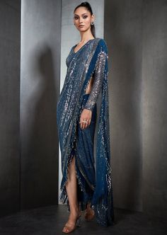 Our draped sari has metallic fringes. Paired with a one-shoulder, cord embroidered blouse. Perfect for a sangeet/ reception. Blue Pre-draped Saree For Festive Evenings, Formal Lehenga With Sequins In Traditional Drape, Formal Lehenga With Sequins And Traditional Drape, Formal Blue Bollywood Pre-draped Saree, Pre-draped Saree With Pallu For Evening Festivals, Pre-draped Saree With Dupatta For Navratri Party, Formal Choli With Sequins And Traditional Drape, Bollywood Style Blue Pre-draped Saree For Party, Festive Evening Pre-draped Saree With Zari Work