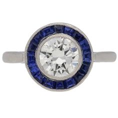 a diamond and blue sapphire ring with an oval center surrounded by round brilliant cut diamonds