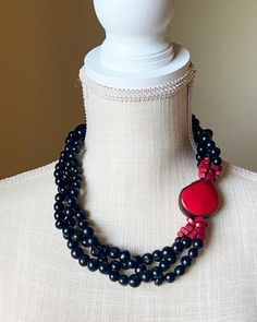 Elegant and feminine, this stunning piece features acai seeds in black and a red tagua nut embellished with tagua nut chips that help elongate the focal point. What a fantastic color combination! You can pair it with even the simplest tee or dress and have a chic look in a second. Because the materials are all natural, each necklace is unique. Some variations in shape and size is to be expected. Tagua, also called the vegetable ivory is the seed of a palm tree that grows in the tropical rainfore Black Multi-strand Wooden Beads Jewelry, Black Multi-strand Wooden Beaded Necklaces, Black Multi-strand Wooden Bead Necklaces, Elegant Black Necklace With Wooden Beads, Elegant Black Beaded Necklace With Wooden Beads, Black Necklaces With Wooden Beads, Unique Black Necklaces With Wooden Beads, Black And Red Necklace, Seed Necklace