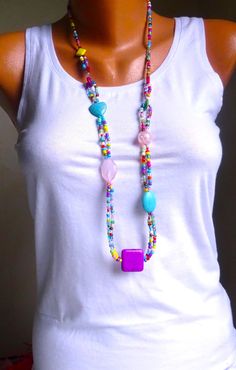 a woman wearing a white tank top and colorful beaded necklace