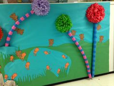 a bulletin board decorated with paper flowers and pom poms in the shape of trees