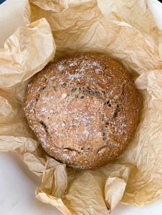 a loaf of bread sitting inside of a paper bag on top of a white plate