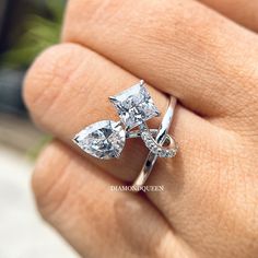 a woman's hand holding a ring with three pear shaped diamonds