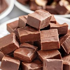 a pile of chocolate pieces sitting on top of a white plate next to other plates