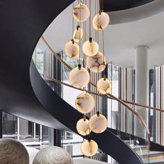 a spiral staircase with marble balls hanging from it's sides and an elegant chandelier in the background