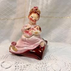 a figurine of a woman holding a baby on top of a red base