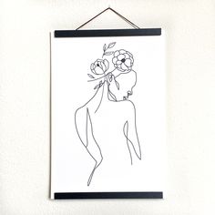 a black and white drawing of a woman with flowers in her hair hanging on a wall