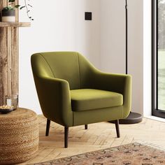 a green chair sitting on top of a hard wood floor next to a lamp and window