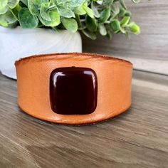 Keeping the natural hue of the rawhide leather, this bracelet features clean, simple lines.  A single brown agate stone bead, sewn into the leather band, gives it contrast for a polished look. The shape of this bracelet gently tapers off at the ends.  Perfect for that casual boho-chic look that you can wear everyday. Fits wrist sizes up to 7 5/8 inches Inside Measurement: adjustable closure makes several sizes with 8 inches the largest size Width 1 1/2 inches at the widest part A metal stud and punched hole are used to fasten the cuff in place. The metal stud can be unscrewed to fit in one of three holes so that you can adjust the size of the wristband.  Over time, as you wear this wristband, the leather will become softer and it will darken which gives it a a very nice aged look. All of m Rectangular Leather Bracelet For Everyday Use, Brown Leather Strap Cuff Bracelet For Everyday, Everyday Brown Leather Strap Cuff Bracelet, Everyday Rectangular Leather Bracelet, Rectangular Leather Bracelets For Everyday, Brown Leather Cuff Bracelet For Everyday, Everyday Rectangular Leather Bracelets, Elegant Adjustable Brown Cuff Bracelet, Everyday Brown Leather Cuff Bracelet