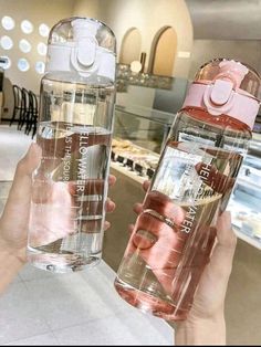 two people holding up water bottles in a store