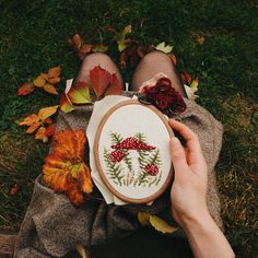 someone is laying on the grass with their feet up holding a cross - stitch