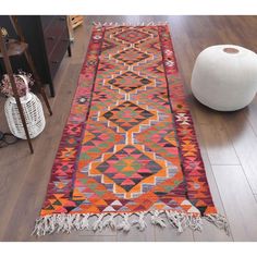 a colorful runner rug with tassels on the floor next to a white ball