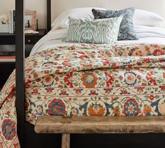 the bed is made up with colorful pillows and blankets on it's headboard