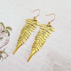 Long antique gold plated fern leaf drop earrings, with your choice of gold plated or surgical steel ear wires.  The leaf measures 2 1/8 inches (55 mm) from top to bottom, and has a textured fern pattern on the front and is plain on the back. They are mid weight earrings.  They come on gold plated or surgical steel hooks, but if you would like a different wire or style please ask me. These earrings come in a gift box. Also now available separately in antique silver and bronze. More earrings here: Gold Leaf-shaped Nickel-free Earrings, Gold-plated Leaf-shaped Earrings, Gold Leaf-shaped Pierced Earrings, Gold Leaf Shaped Metal Jewelry, Yellow Gold Leaf-shaped Brass Earrings, Gold Leaf-shaped Earrings For Gift, Gold Leaf Earrings For Gift, Gold Leaf Shaped Brass Jewelry, Minimalist Gold Leaf Earrings