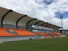 an empty baseball stadium with orange seats and the sky in the backgrouds