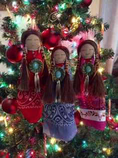 three dolls are hanging on the christmas tree