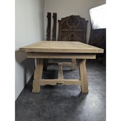 a wooden table sitting on top of a floor next to a chair in a room