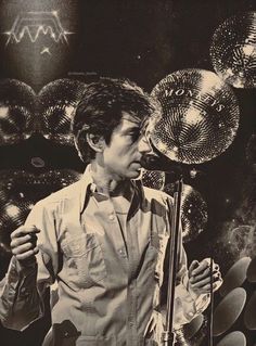 a man standing in front of a microphone with disco balls on the wall behind him