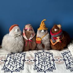 four stuffed animals are lined up on a bed with a blue wall in the background