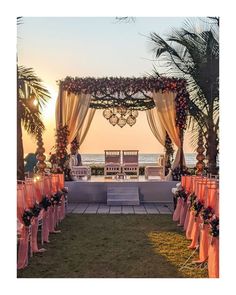 an outdoor ceremony set up with orange and pink decorations on the grass, overlooking the ocean