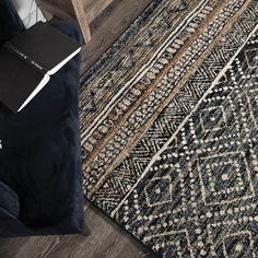 a black and white area rug with an intricate design on the floor next to a wooden table