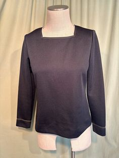 This is a sweet vintage top from the 70s.  Labeled My Latest Leslie Fay. No size tags. The bust measures 38", see measurements below. This classic top is made of black polyester. It has beige trim around the square neckline, along with double rows of beige top stitching. The same stitching trims the sleeve cuffs. It is a pullover top that zips down the back with a nylon zipper.    The top is in very good condition!  No damage or soil. Super cute!  If you have never worn vintage before, please measure yourself!! Vintage sizes run smaller than today's sizes, know your measurements before buying! Bust measured from side seam to side seam at the underarm: 18" for a 36" bust Waist measured from side seam to side seam at hem: 19" for a 38" hemline Shoulders: 14" Length measured from shoulder to Beige Trim, 70s Tops, Vintage Blouses, Beige Top, Blouse Vintage, Top Stitching, Square Neckline, Vintage Tops, Vintage 70s