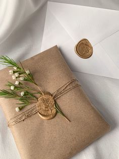 an envelope with a wax stamp and flowers tied to it, next to a penny