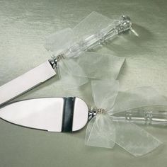 two knifes with bows on them sitting next to each other in clear plastic bags