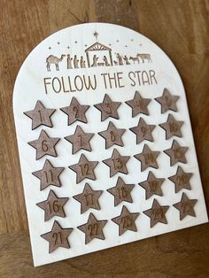 a wooden calendar with brown stars and the words follow the star written in white on it