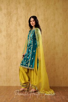 "Teal Blue Royal Silk Velvet Kameez with Hand Embroidery and Chartreuse Yellow Silk Salwar: A Luxurious Punjabi Suit for Women" This stunning Punjabi suit combines the richness of teal blue silk velvet with the delicate hand embroidery to create a truly regal look. The kameez features intricate hand embroidery, adding to its luxurious appeal. The salwar is made of chartreuse yellow silk fabric, also with hand embroidery, which perfectly complements the teal blue kameez. To complete the tradition Designer Turquoise Sets With Resham Embroidery, Turquoise Sharara With Resham Embroidery For Eid, Bollywood Style Embroidered Turquoise Sets, Designer Turquoise Set For Eid, Turquoise Set For Eid, Unstitched Turquoise Salwar Kameez With Resham Embroidery, Turquoise Anarkali Sharara For Eid, Turquoise Dabka Work Sets For Eid, Eid Turquoise Sets With Dabka Work