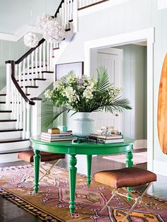 a living room with a green table and stairs