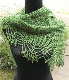 a close up of a mannequin wearing a green knitted shawl with leaves on it