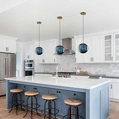 a kitchen with white cabinets and blue island