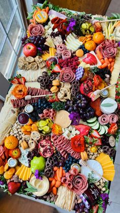 a table covered with lots of different types of food on top of each other in front of a window