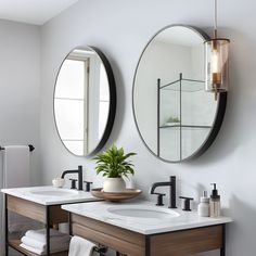 two round mirrors are above the sinks in this modern bathroom with white walls and wood cabinets