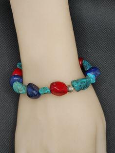 This lovely chunky bracelet is Handmade with all genuine gemstone and sterling silver.   Large Nuggets of blue turquoise, lapis lazuli, and red bamboo Coral are randomly set with sterling silver beads and a sterling silver size adjustable toggle clasp. This bracelet measures 9 1/2 inches and will fit a size 6 1/2 - 8 inch wrist. Bracelet will be much longer than a normal size bracelet to allow for the width of the gemstone nuggets. This bracelet will be shipped to you in a complimentary gift box Southwestern Natural Stones Beaded Bracelet Gift, Red Bamboo, Nugget Bracelet, Bamboo Coral, Wrist Bracelet, Chunky Bracelet, Hippie Bracelets, Chunky Bracelets, Genuine Turquoise