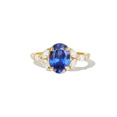 a blue sapphire and diamond ring with two diamonds on the band, set in yellow gold