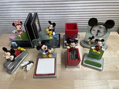 several mickey mouse figurines sitting on top of a table next to a clock