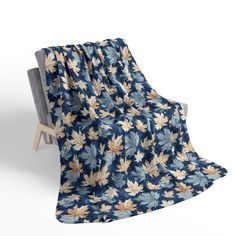 a chair with a blanket on it that has blue and yellow leaves all over it